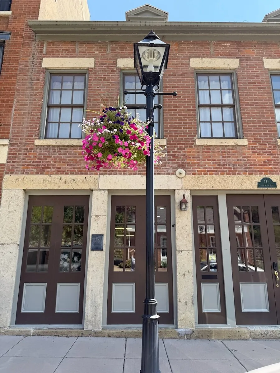 The storefront seen straight on from the sidewalk, beneath a cast-iron lamp post and a hanging flower basket