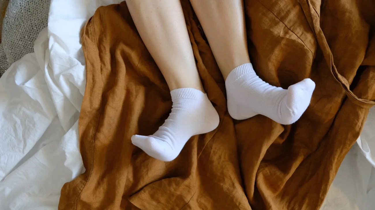 Feet in cream wool socks on brown textile