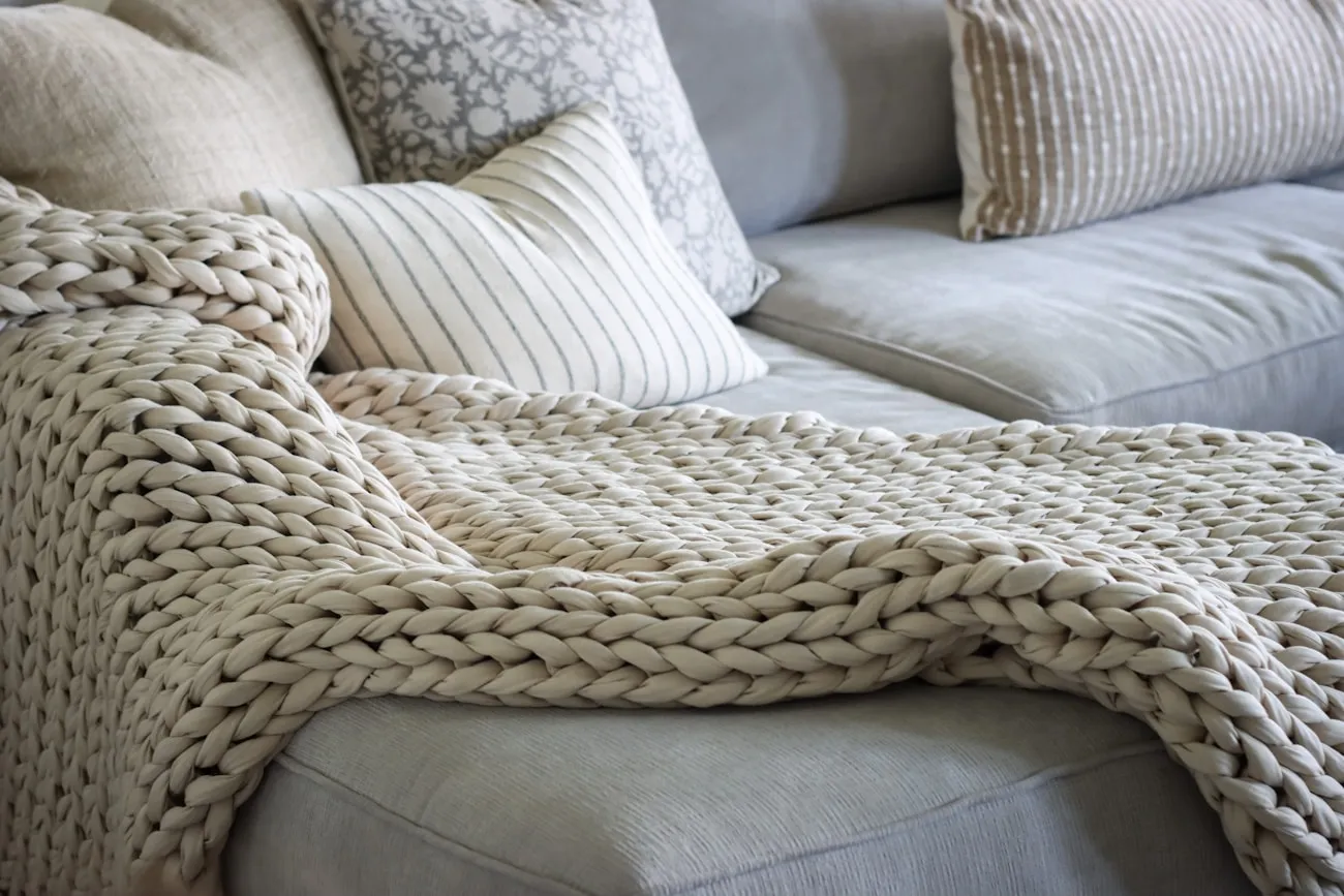A knitted throw folded over a sofa