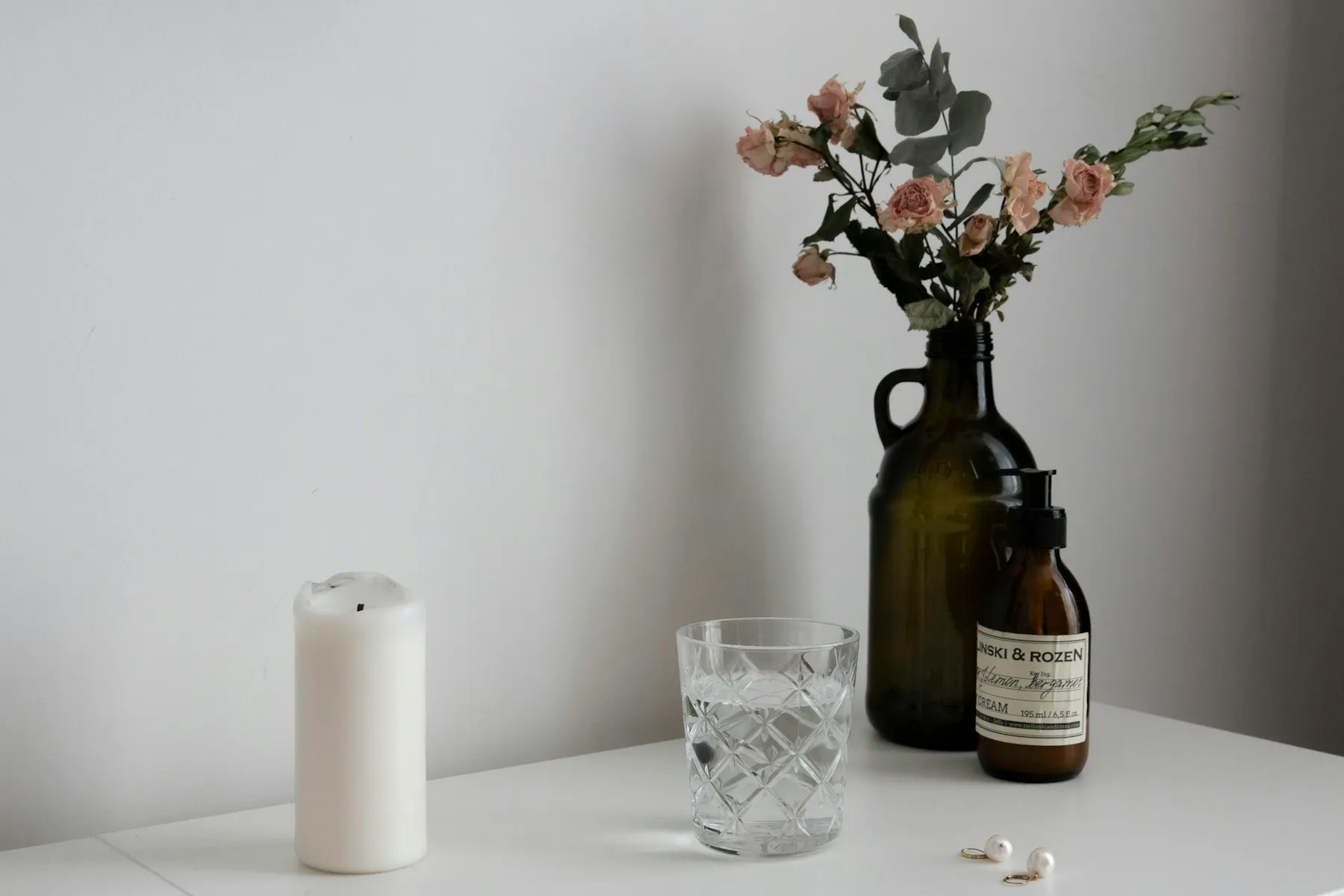 A white pillar candle beside a glass holder